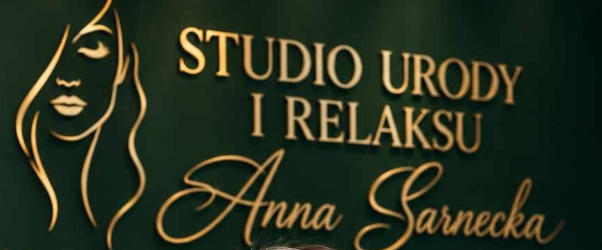 Złoty szyld Studio Urody i Relaksu Anna Sarnecka na zielonej ścianie studia
